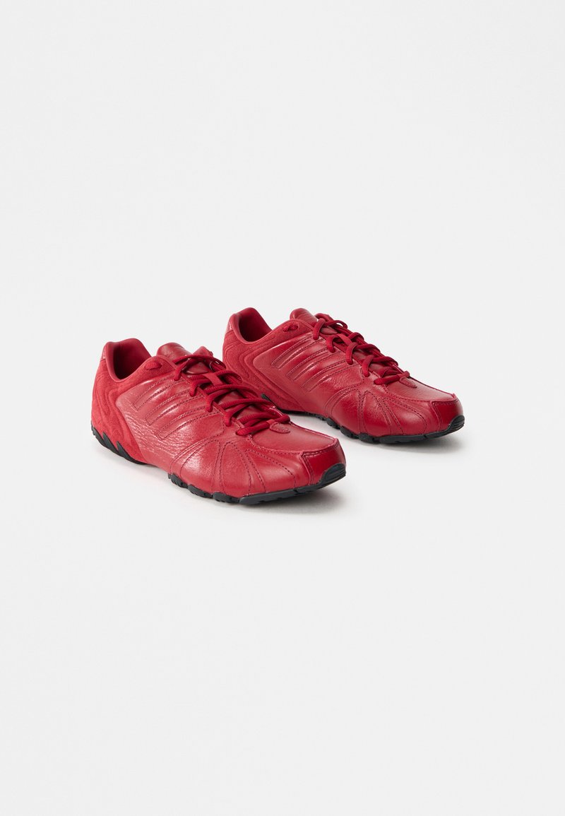 Rote Sportschuhe aus Leder und Wildleder, mit einer strukturierten Oberfläche, Schnürverschluss und schwarzem Gummiaus outsole mit gebogenem Design.