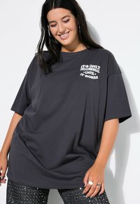 Czarnoszary, oversize t-shirt wykonany z bawełny, z krótkim rękawem i okrągłym dekoltem, z białym napisem z przodu.