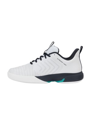 Chaussure de sport blanche et noire avec lacets noirs, languettes, motifs en chevron sur le côté et texte "ULTRASHOT LIGHT" près de la cheville.