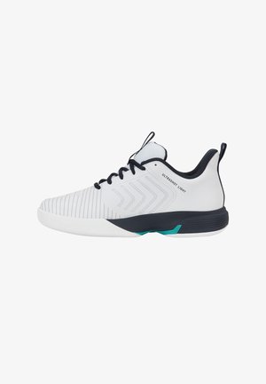 Chaussure de sport blanche et noire avec lacets noirs, languettes, motifs en chevron sur le côté et texte "ULTRASHOT LIGHT" près de la cheville.