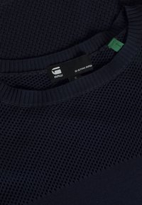 Mörkblå tröja i strukturerad meshstruktur och slät stickning. Har en ribbad halsringning och G-Star RAW-märke i svart.