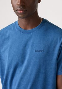 Blå bomull t-skjorte med korte ermer, rund hals, og subtil Levi's-logo brodert i mørkere blått på venstre bryst.