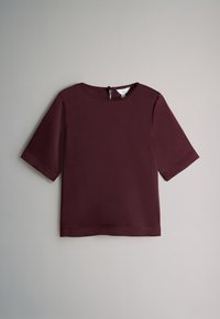 Bordeauxrotes Kurzarmoberteil mit rundem Ausschnitt, glatter Oberfläche und einer Aussparung mit Verschluss am Rücken. Schlichte, klare Linien ohne sichtbare Muster.