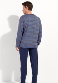 Men's pajama set featuring a patterned long-sleeve top in blue with multicolored geometric design and solid navy pants, cotton material.