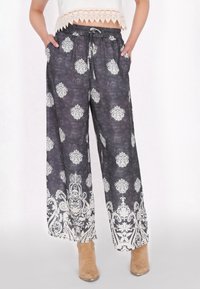 Wijdvallende broek in donkergrey stof met witte bloemmotieven, elastieken tailleband, trekkoord en zijzakken. Verfraaid met complexe randen.