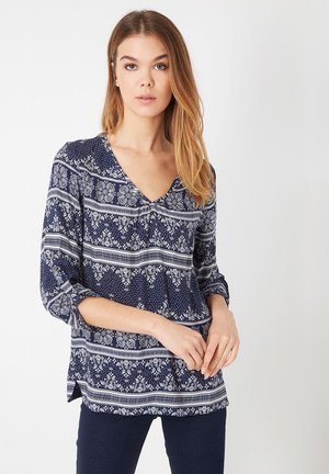 Blusa marino con escote en V, mangas tres cuartos y un patrón floral y de rayas. Tejido suave con un corte relajado y aberturas laterales.