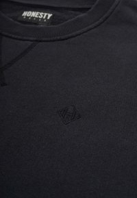 Dark navy sweatshirt featuring a round neck, ribbed edges, and a small embossed logo on the front. Soft fabric with a smooth texture.