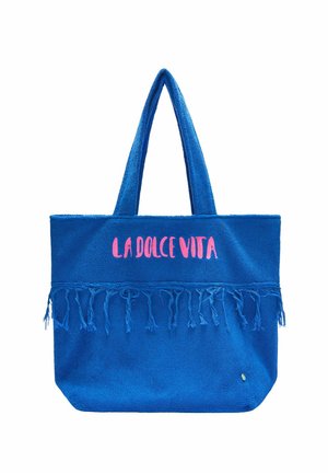 Blaue Tragetasche mit langen Henkeln, Fransen-Detail und pinkem Schriftzug "LA DOLCE VITA" auf der oberen Vorderseite.