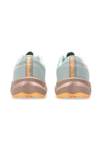 Des chaussures de sport bleu clair avec une tige texturée, des accents dorés et une semelle courbée et rembourrée dotée d'un motif de semelle orange contrastant.
