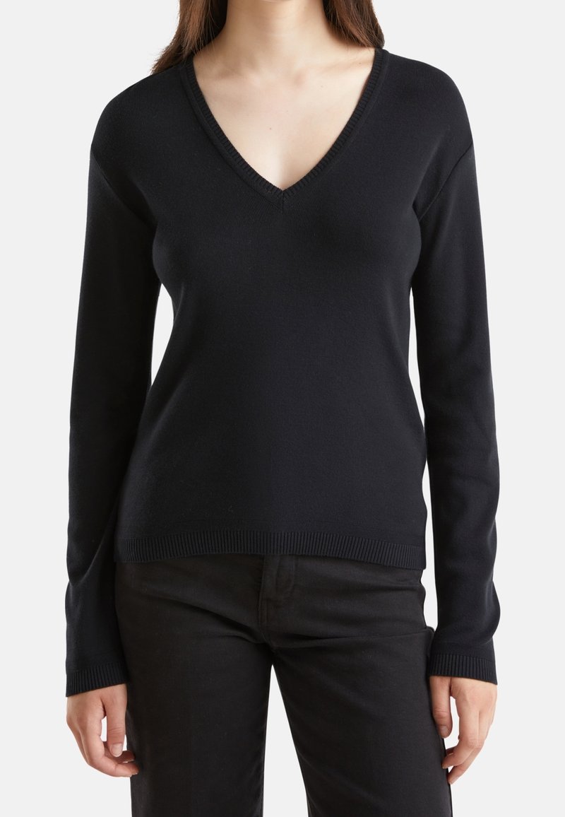 Pull noir en maille avec un col en V, des manches longues, et des poignets et un ourlet côtelés, présentant une silhouette ajustée et une texture lisse.