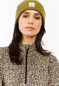 Top de forro polar de estampado de leopardo beige con cuello de cremallera y gorro de punto acanalado verde con parche de logo. Textura suave y diseño ajustado.