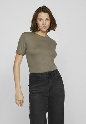 Camiseta ajustada verde oliva de manga corta y cuello redondo, combinada con jeans negros de cintura alta que presentan una textura de denim clásica.