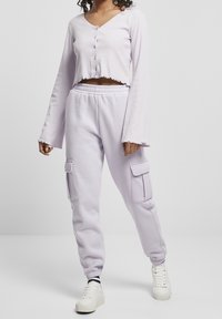 Jasnofioletowa krótka bluzka z długim rękawem, z zapięciem na guziki i postrzępionym dołem, zestawiona z pasującymi joggerami z bocznymi kieszeniami i ściągaczami.