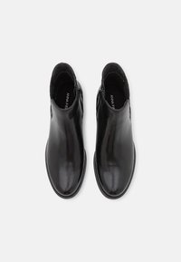 Černé kožené kotníkové boty s hladkým povrchem, kulatou špičkou, bočním zipem a minimalistickým designem, který zdůrazňuje elegantní siluetu.