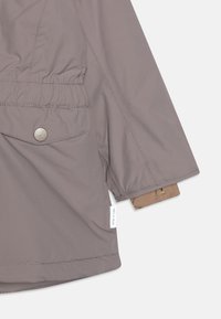 Grau wasserdichte Jacke mit elastischem Bund, Seitentaschen und einem hellbraunen Innenfutter. Mit Druckknöpfen und Markenlabel versehen.