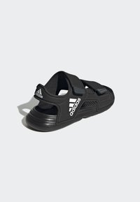 Sorte sandaler med justerbare stropper, mesh-sider og struktureret sål. Har hvid branding på stroppen og panelet.