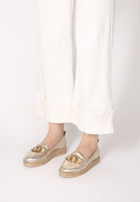 Goldene Espadrilles mit Lederoberteil und gewobener Jutesohle; verf�ügen über ein goldenes Kettenakzent an der Vorderseite und ein rundes Design der Zehenpartie.