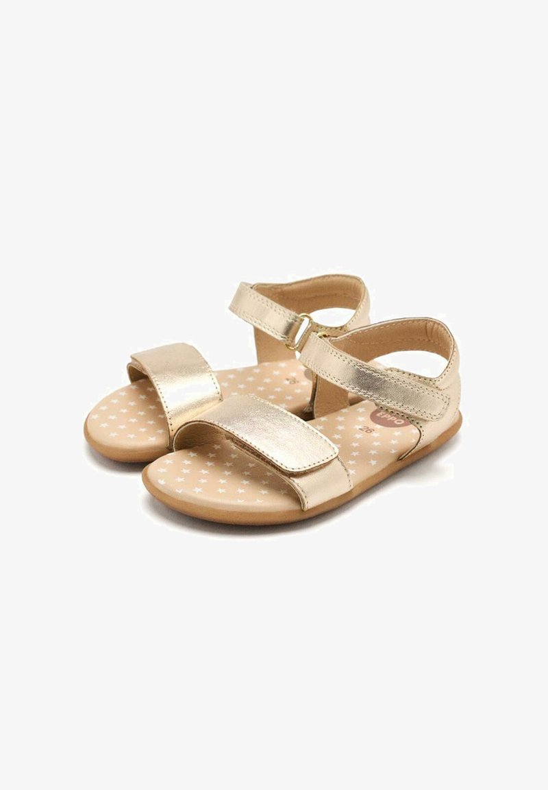 Sandalias metálicas doradas con dos correas anchas y un detalle de hebilla. La plantilla presenta un fondo beige con patrones de estrellas blancas. Diseño ligero.