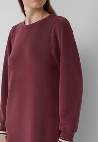 Bordeauxfarbener Langarm-Sweatshirt mit rundem Halsausschnitt, ausgestattet mit gerippten Bündchen in Weiß und Bordeaux, glatte Textur.