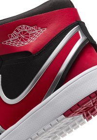 Rot-schwarzer High-Top-Sneaker mit einem strukturierten Leder-Obermaterial, silbernen Akzenten und einer weißen Gummisohle, die ein detailliertes Profilmuster aufweist.