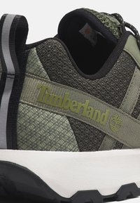 Grüner Textilsneaker mit Mesh-Obermaterial, hellgrauen Akzenten, Timberland-Logo und Gummisohle. Verfügt über Schnürsenkel und gepolsterten Schaft.