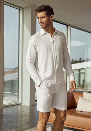 Witte linnen blouse met lange mouwen en een button-down kraag, gecombineerd met bijpassende shorts. Gladde textuur, lichtgewicht ontwerp en ontspannen pasvorm.