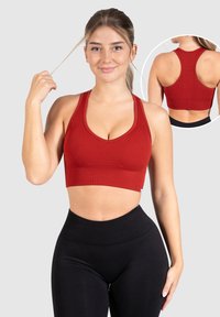Sujetador deportivo rojo de canalé con escote en forma de scoop y diseño de espalda nadadora, con un acabado texturizado y corte a media longitud, combinado con leggings negros de cintura alta.