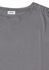 T-shirt gris clair à col rond avec un détail de volants froncés à l'épaule et une étiquette cousue indiquant « CECIL » à l'intérieur du col.