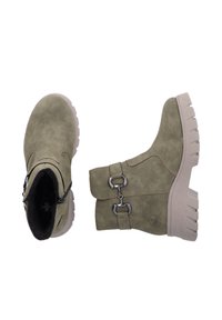 Bottes chelsea vert olive en suède doux avec une surface texturée, dotées d'une semelle beige épaisse et de boucles argentées pour les détails.