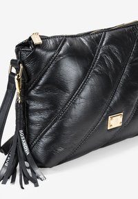 Clutch de cuero negro acolchado con un acento de hardware en tono dorado, cierre de cremallera y una correa desmontable con borlas de cuero.