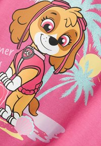 Pink fabric featuring a cartoon dog with brown fur and pink accents, wearing a vest. Background includes palm trees and a sun.
