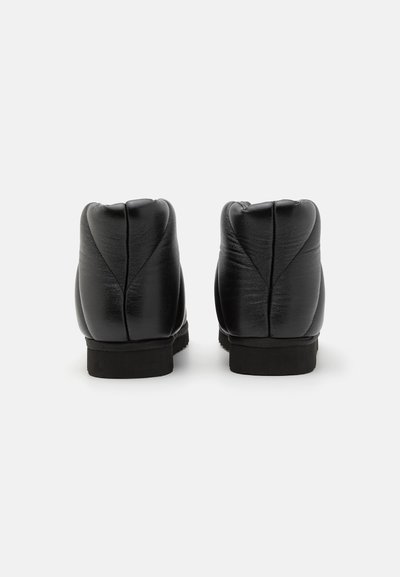 Zwarte enkellaarzen met een gladde leren textuur, ronde achterkant en subtiele stikseldetails. Voorzien van een duurzame rubberen zool voor grip.