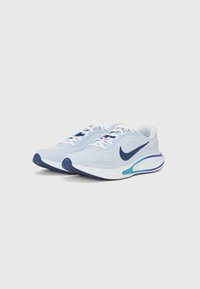 Light blue running shoes with a textured upper, white laces, and a dark blue swoosh logo. Features a cushioned sole with color accents.