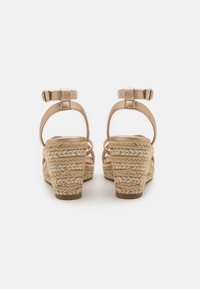 Wedge sandals with a metallic beige upper and woven jute heel. Features ankle straps and a textured platform for added stability.