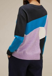 Pull en tricot avec des blocs de couleur géométriques en marine, bleu, violet pastel et blanc. Texture douce, col rond et poignets côtelés.