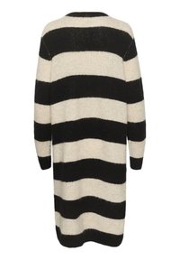 Robe en tricot avec de larges rayures noires et crème, manches longues, col rond et fentes sur les côtés pour faciliter le mouvement.