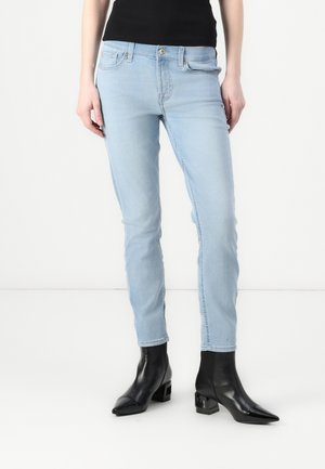 Light blue skinny jeans with a classic five-pocket design, paired with black ankle boots featuring a square heel and pointed toe.