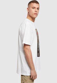 Hvid bomulds T-shirt med grafisk tryk på forsiden. Løs pasform med korte ærmer og rund hals. Blød tekstur.