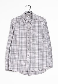 Camicia a quadri grigia e bianca con colletto, maniche lunghe, taschino sul petto e dettagli con orlo sfrangiato. Realizzata in un tessuto morbido e testurizzato.
