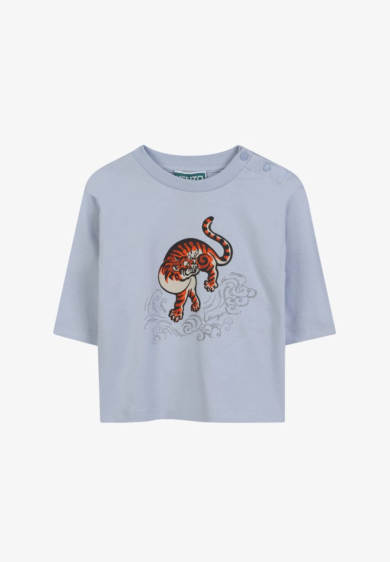 T-shirt bleu clair à manches courtes avec un col rond, présentant un tigre brodé en orange et noir, ainsi que des motifs de vagues en argent.