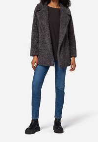 Gray textured coat with a notched collar, double-breasted front, paired with blue jeans and black chunky ankle boots.