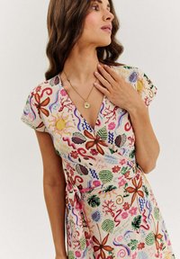 Květinové zavinovací šaty ve světlých pastelových barvách, s motivy květin, motýlů a abstraktních tvarů. Krátké rukávy, detail vázání v pase.