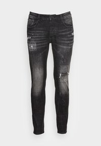 Czarne dżinsy z denimu z przetarciami, z wyblakłym wykończeniem, dziurami na kolanach i subtelnymi plamkami farby na całym materiale.