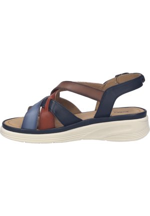 Dámská sandála s měkkou bílou podešví a překříženými koženými pásky v modré, hnědé a rezavé barvě, vybavená nastavitelným páskem kolem kotníku.