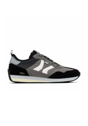 Zapatilla deportiva gris y negra con rayas blancas en los lados, cierre de cordones y el número 2003 impreso cerca del talón.
