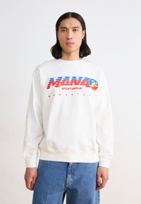 Sweatshirt blanc en mélange de coton, avec un imprimé graphique coloré aux accents rouges, bleus et jaunes. Coupe décontractée avec des poignets côtelés.