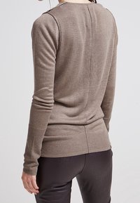 Bruine gebreide trui met lange mouwen, geribbelde zoom en achternaaddetails. Zachte textuur met een getailleerd ontwerp.