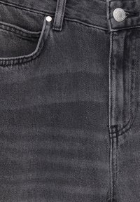 Black denim jeans featuring a smooth texture, five-pocket design, and silver metal button with brand engraving.