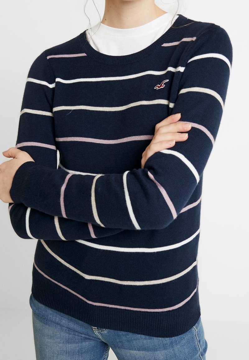 Granatowy sweter w paski z białymi i jasnoróżowymi poziomymi pasami, okrągłym dekoltem i prążkowanymi mankietami. Miękki materiał dzianiny o dopasowanym kroju.