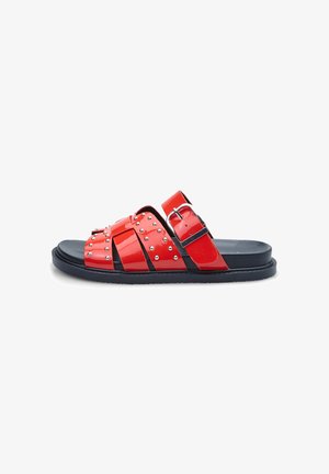 Rode gepatineerde leren sandalen met brede banden, zilveren studs en een zwarte rubberen zool. Voorzien van een verstelbare gesp op één band.